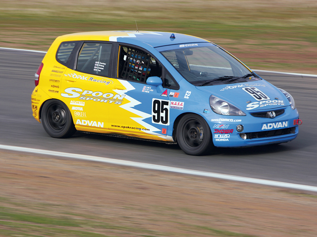 Photo of a first generation Honda Fit in a blue and yellow racing paint job.