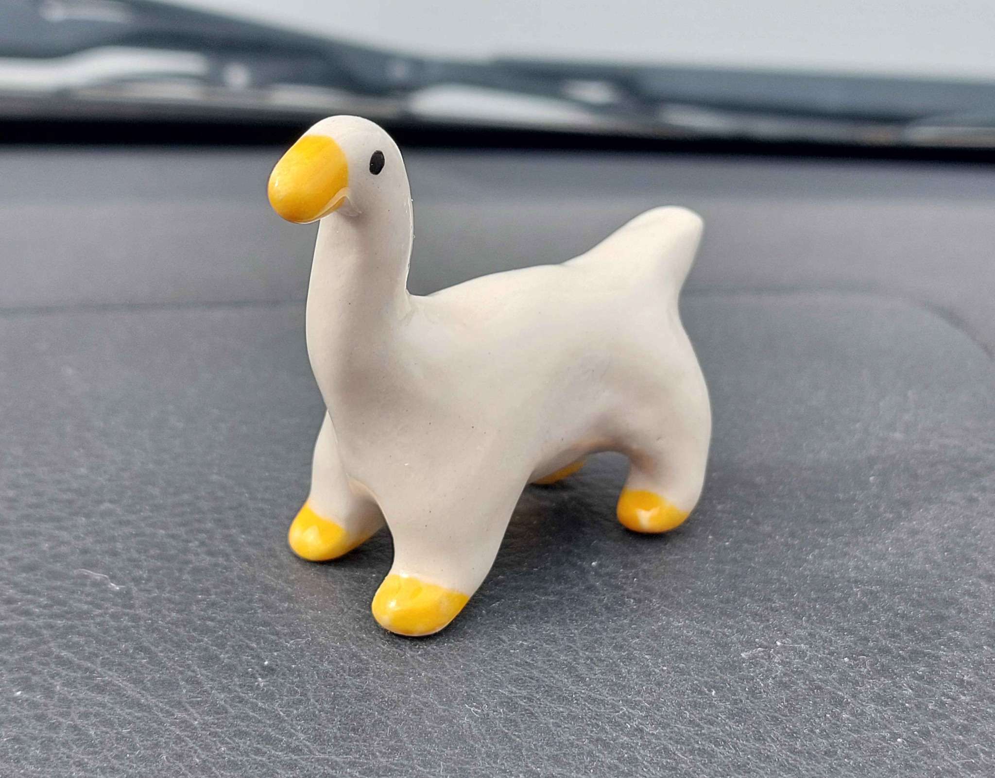 photo of a miniature statuette of a goose, whose torso is extended to give him four feet like a horse.