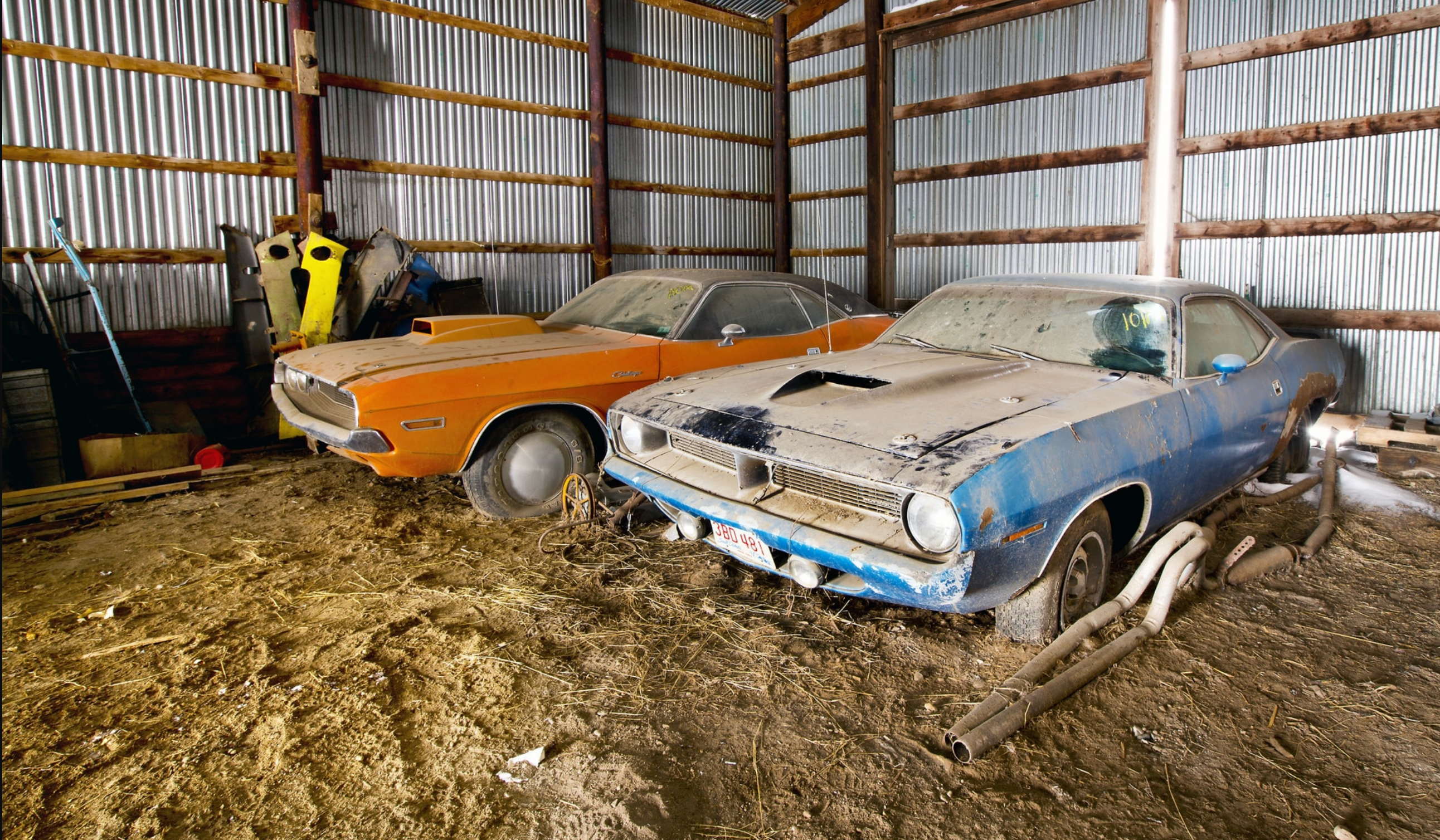 photo of two dusty old cars in a garage.
